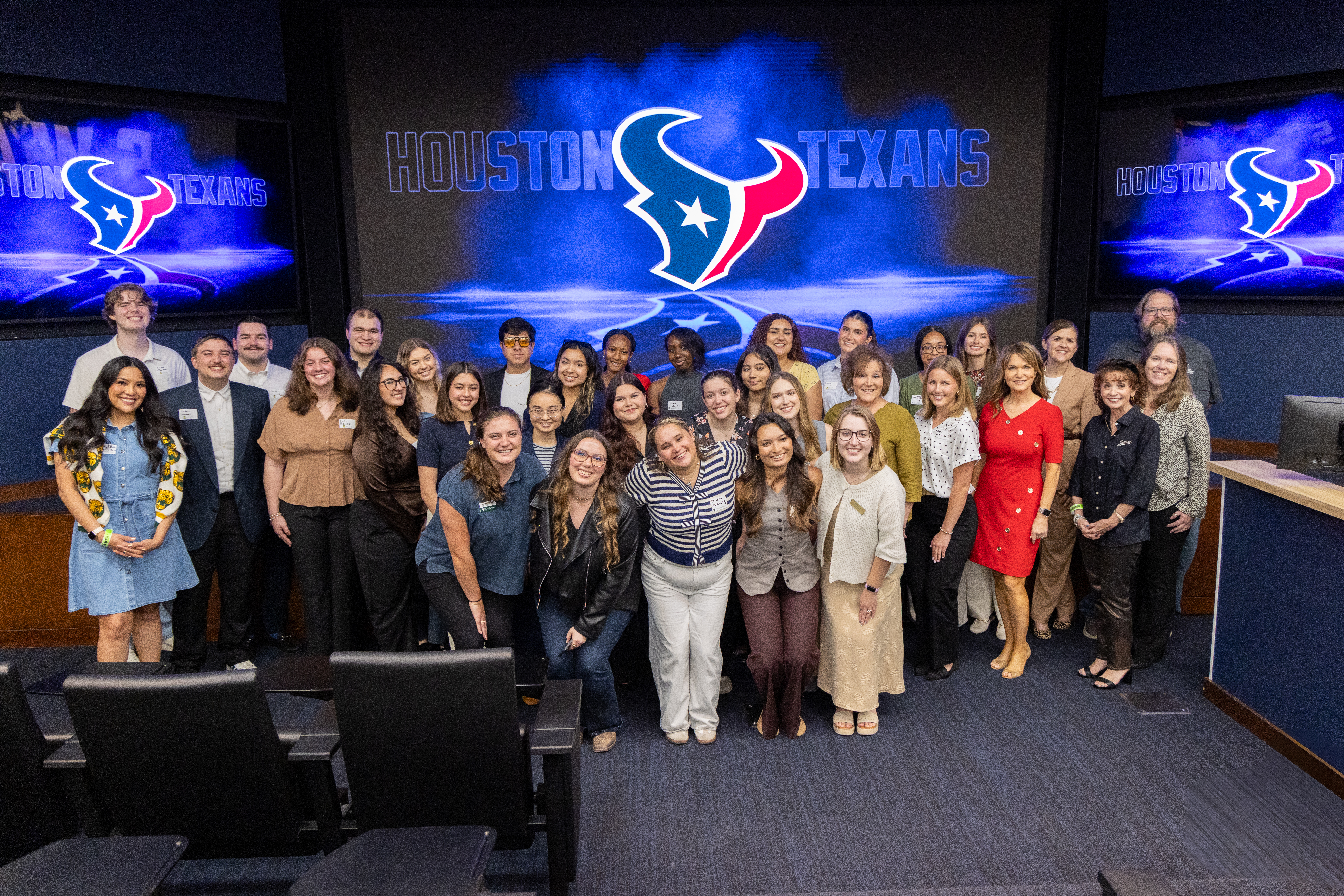 Group photo in front of the Houston Texans logo. 